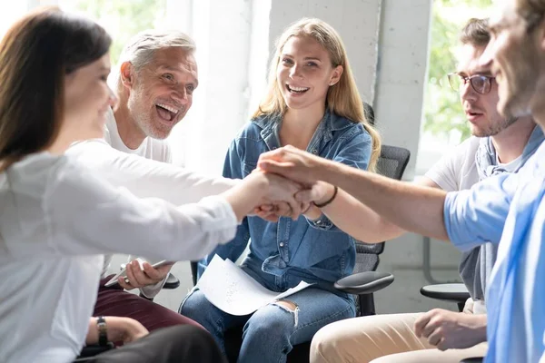 Mutlu iş ekibi elleri ofiste beşlik çakıyor..