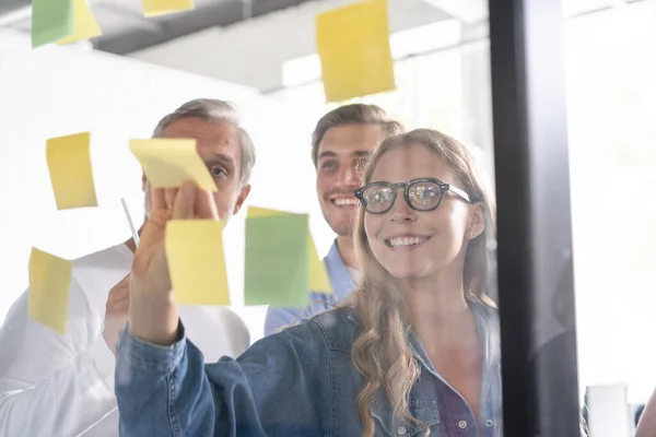 Affärsmän träffas på kontoret och använda post det anteckningar för att dela idé. Brainstorming-konceptet. Klisterlapp på glasvägg — Stockfoto