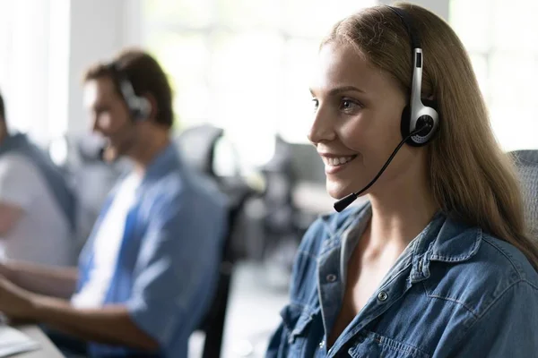 ¿Cómo puedo ayudarle Hermosos trabajadores del centro de llamadas en los auriculares están trabajando en la oficina moderna — Foto de Stock