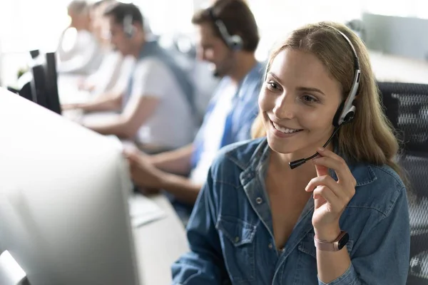 ¿Cómo puedo ayudarle Hermosos trabajadores del centro de llamadas en los auriculares están trabajando en la oficina moderna — Foto de Stock