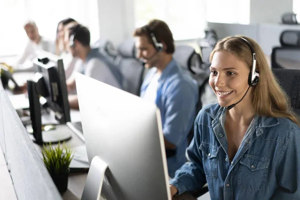 Hoe kan ik u helpen Mooie call center werknemers in hoofdtelefoon werken op modern kantoor — Stockfoto