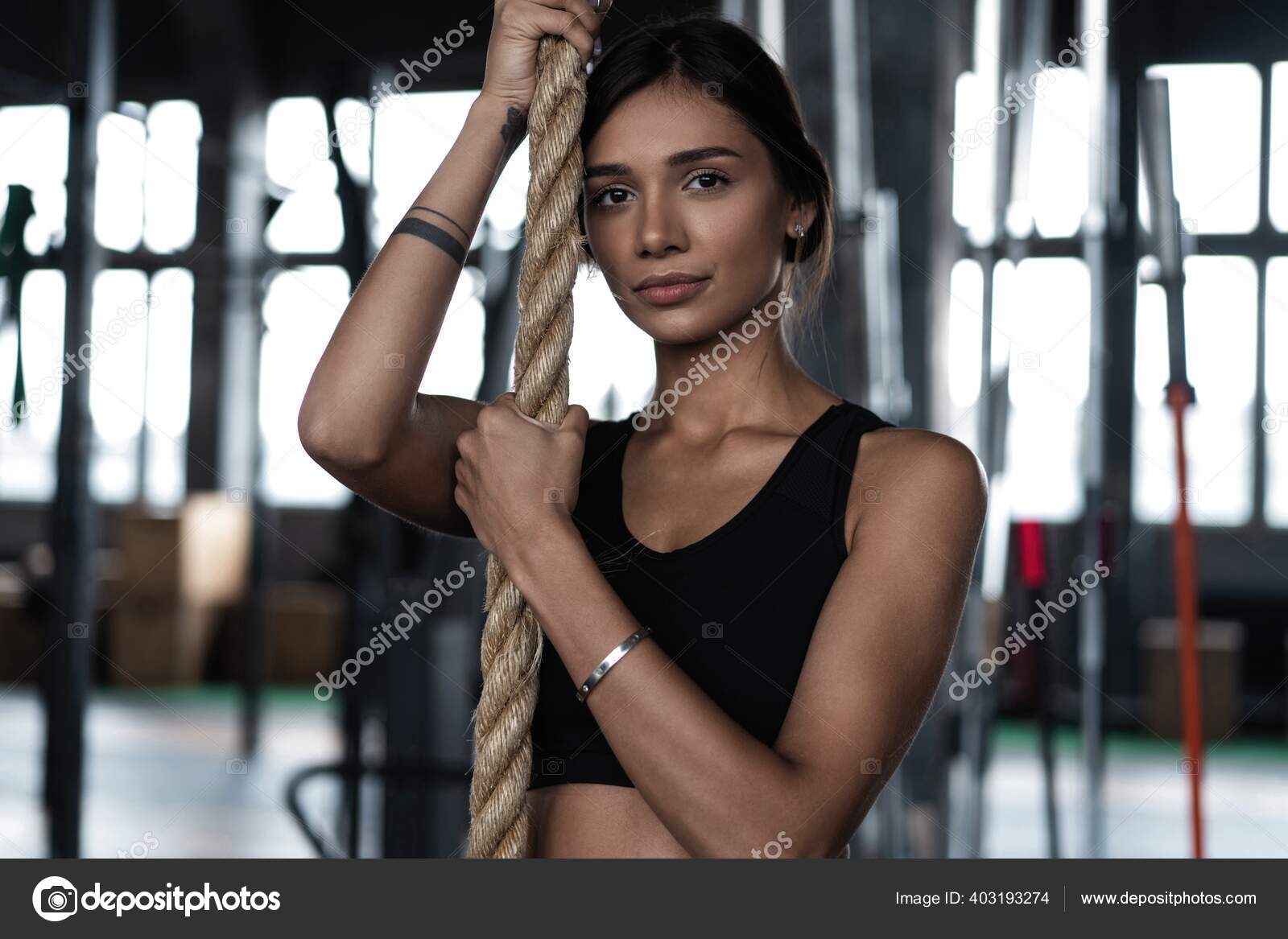 Exercising woman holding gymnast rings and looking away. Female