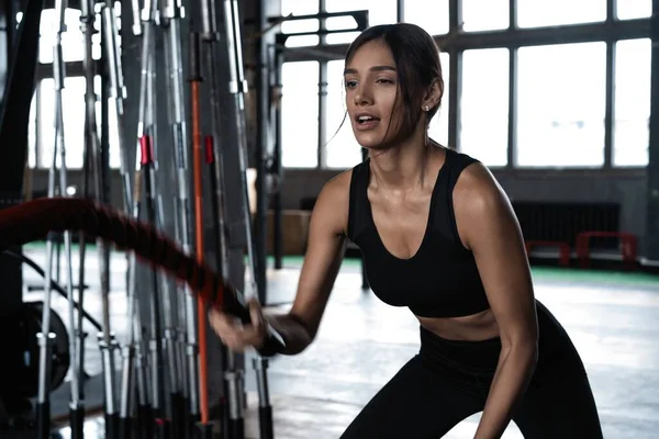 力大无穷、有魅力的女子交叉运动健美教练在体育馆里用绳索进行战斗锻炼 — 图库照片