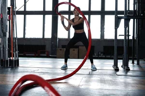 Ισχυρό ελκυστική μυϊκή γυναίκα CrossFit εκπαιδευτή κάνει προπόνηση μάχη με σχοινιά στο γυμναστήριο — Φωτογραφία Αρχείου