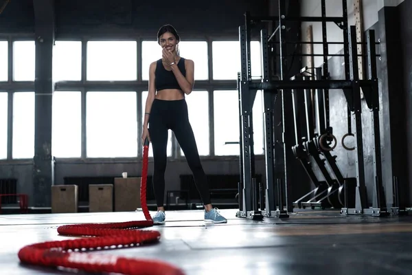 Junge Frau beim Krafttraining mit schweren Seilen im Fitnessstudio — Stockfoto