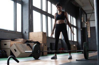Çekici, güçlü, kaslı kadın vücut geliştirici ağır iş yapıyor. Crossfit spor salonunda halter kaldırıyor..