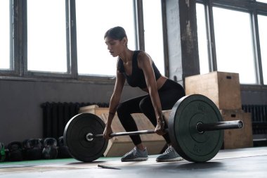 Çekici, güçlü, kaslı kadın vücut geliştirici ağır iş yapıyor. Crossfit spor salonunda halter kaldırıyor..