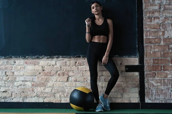 Esportivo caucasiano cross fit mulher com suporte de bola de fitness no ginásio, olhar para a câmera — Fotografia de Stock