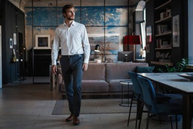 Beyaz gömlekli yakışıklı genç iş adamlarıyla dolu bir odada kendi ofisinde yürüyordu..