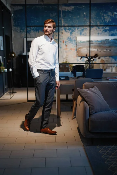 Comprimento total de belo jovem empresário de camisa branca andando pela sala em seu próprio escritório. — Fotografia de Stock