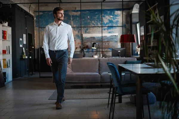 Pełna długość przystojny młody biznesmen w białej koszuli spacery przez pokój w jego własnym biurze. — Zdjęcie stockowe