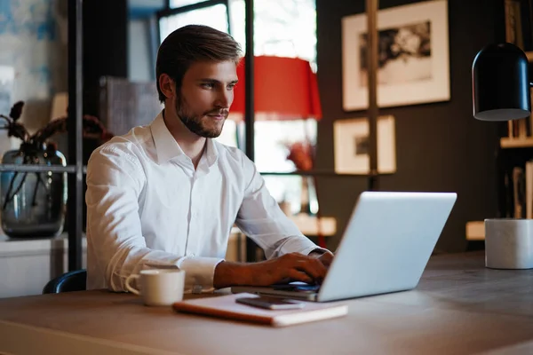 Schöner Geschäftsmann arbeitet im Büro mit Laptop — Stockfoto