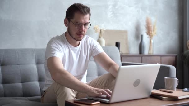 Man thuis op de bank, werkt op afstand, geniet van zijn werk, werkt graag als freelancer — Stockvideo