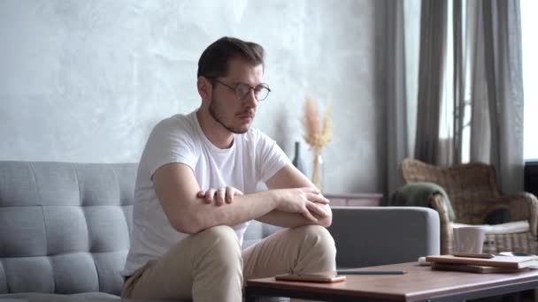 Pensive Young man Sitting on Sofa and Thinking at Home. — Stock Video