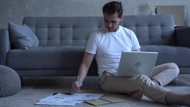 Focused man freelancer sitting on floor in cozy living room using computer — Stock Video