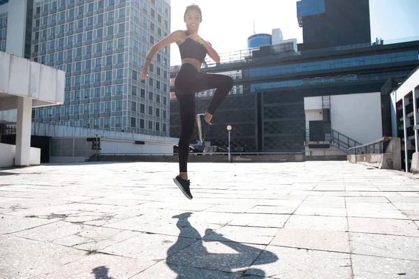 Slim femme brune porte des vêtements de sport sautant pendant son entraînement de fitness. — Photo