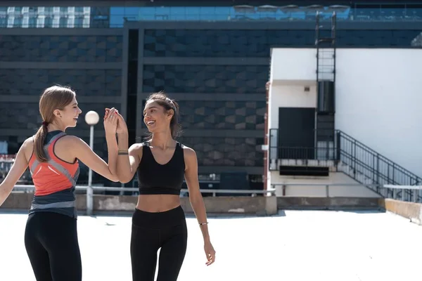 Deux femmes gaies en tenue de fitness donnant cinq tout en courant dans la ville — Photo