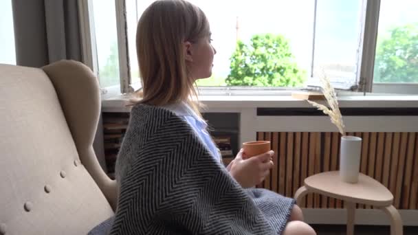 Ung attraktiv kvinna dricka kaffe sitter på stol i modern lägenhet. — Stockvideo