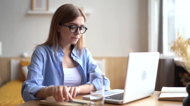 Вид збоку концентрована молода бізнес-леді, що працює на комп'ютері вдома — стокове відео