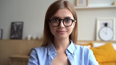 Evde konuşan kameraya bakan genç bir kadın, webcam 'e konuşan bir kadın.