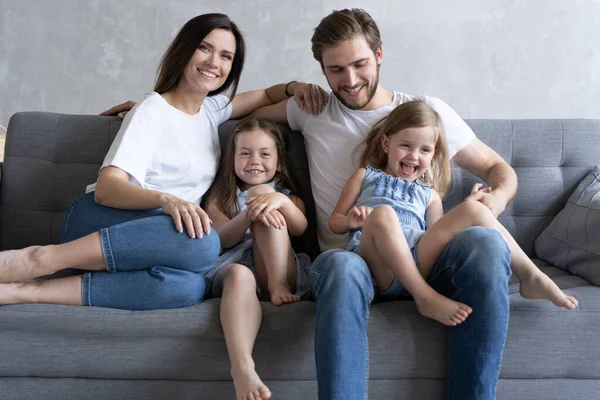 Vrolijke familie thuis zittend op de bank. — Stockfoto