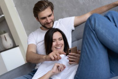 Mutlu çift, evdeki koltukta oturmuş akıllı bir telefonla medyadan zevk alıyor..