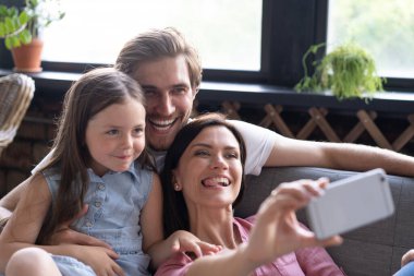 Neşeli bir aile ve çocuklar gülüyor. Akıllı telefondan selfie çekiyorlar.