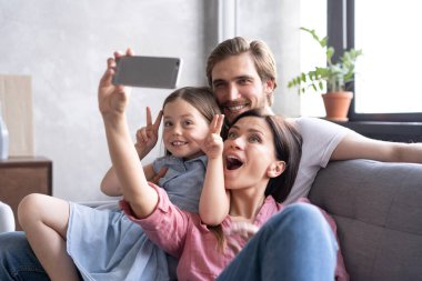 Neşeli bir aile ve çocuklar gülüyor. Akıllı telefondan selfie çekiyorlar.