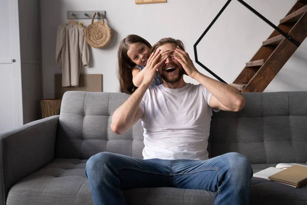 happy father and daughter hugging and sitting on sofa.