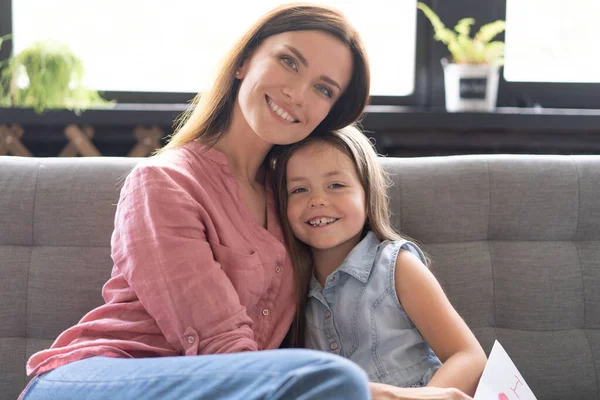 Mother hugging her daughter on the sofa. — Stock Photo, Image