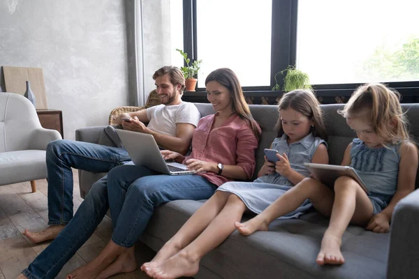 Современные семейные ценности. Отец, мать и дочери используют электронные устройства — стоковое фото