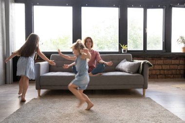 Sakin bir kadın evdeki kanepede yoga egzersizlerine konsantre olurken iki gürültücü çocuk gülüyor, koşuyor.