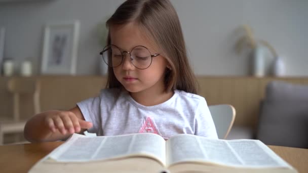 かわいいですスマート小学生女の子読書本でホームテーブル — ストック動画