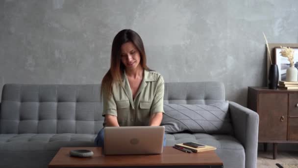 Eccitato giovane donna vincitore guarda computer portatile celebra il successo online sedersi sul divano — Video Stock