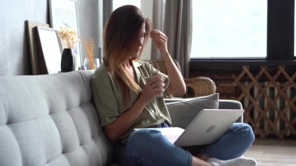 快乐的女人带着笔记本电脑在沙发上放松，在网上商店购物 — 图库视频影像