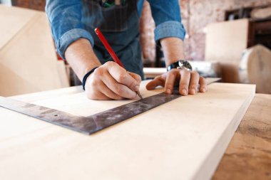 Marangoz, marangozhanede marangoz olarak çalışıyor. Bir adam marangozhanede çalışıyor..