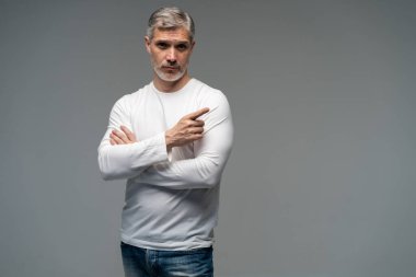 Yakışıklı orta yaşlı bir adam. Gri arkaplandan kameraya bakıyor..