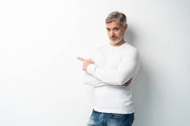 Yakışıklı orta yaşlı bir adam sunar ve elinde avucuyla beyaz arka plandan kameraya bakar..