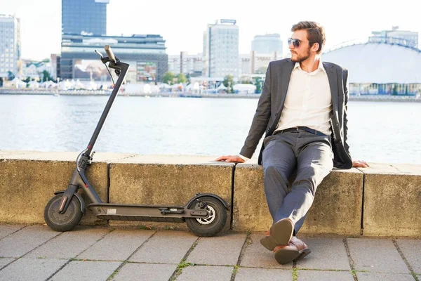 Egy fiatal, modern férfi elektromos robogót használ a városi utcában. Modern és ökológiai közlekedési koncepció. — Stock Fotó