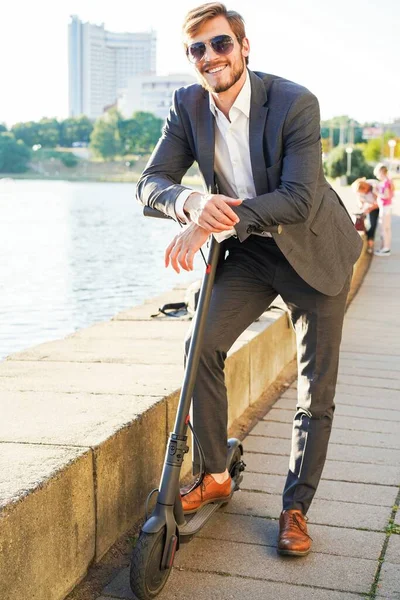 Young modern man using electric scooter on city street. Modern and ecological transportation concept. — Stock Photo, Image