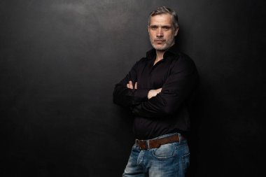 Orta yaşlı yakışıklı bir adam siyah bir arkaplan önünde fotokopi alanı ile poz veriyor..