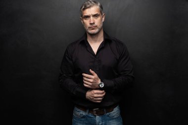 Orta yaşlı yakışıklı bir adam siyah bir arkaplan önünde fotokopi alanı ile poz veriyor..