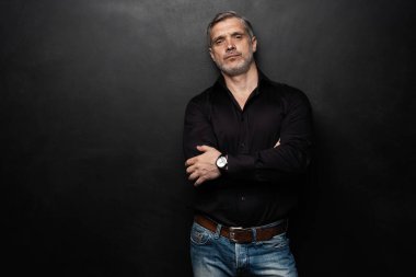 Orta yaşlı yakışıklı bir adam siyah bir arkaplan önünde fotokopi alanı ile poz veriyor..