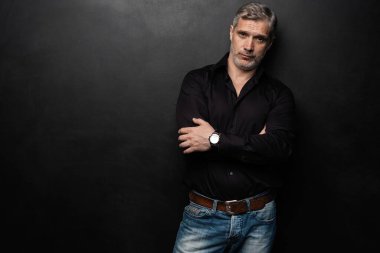 Orta yaşlı yakışıklı bir adam siyah bir arkaplan önünde fotokopi alanı ile poz veriyor..