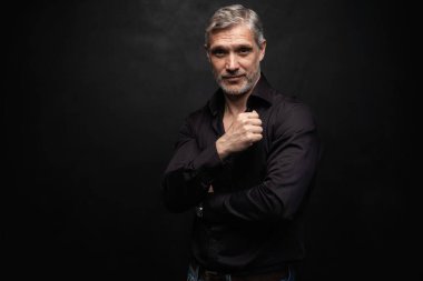 Orta yaşlı yakışıklı bir adam siyah bir arkaplan önünde fotokopi alanı ile poz veriyor..
