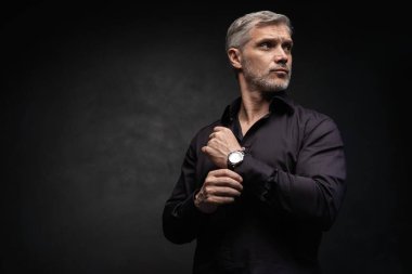 Orta yaşlı yakışıklı bir adam siyah bir arkaplan önünde fotokopi alanı ile poz veriyor..