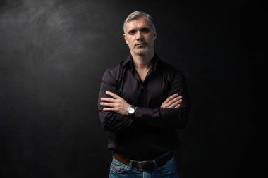 Orta yaşlı yakışıklı bir adam siyah bir arkaplan önünde fotokopi alanı ile poz veriyor..
