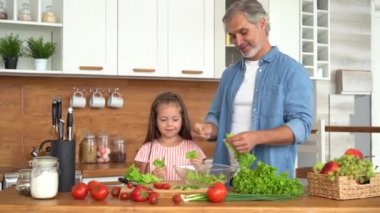 Genç baba çocuklara sağlıklı yemek yapmayı, sebze salatası kesmeyi öğretiyor.