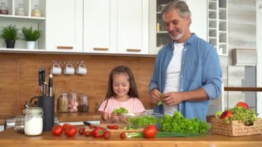 Genç baba çocuklara sağlıklı yemek yapmayı, sebze salatası kesmeyi öğretiyor.