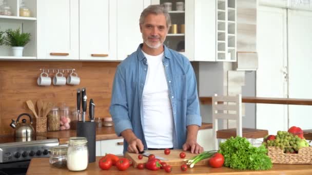 Portrét sebevědomého muže stojícího v kuchyni, usmívajícího se, hledícího do kamery. — Stock video